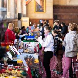 People interacting with holiday vendors in Great Hall
